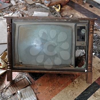 Vintage broken television tv set with wooden frame on dirty floor.