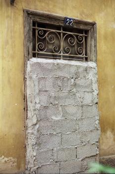 Vintage door with decorative metal swirl pattern blocked by concrete blocks.