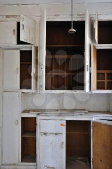 Empty cupboards in the dusty kitchen of an abandoned house.