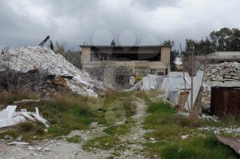 Abandoned factory exterior and pile of marble scrap and industrial debris.