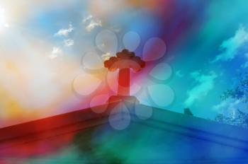 Mausoleum cross against blue sky. Bright sunlight lens flare through painted glass digital composite abstract blur.