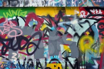 Textured wall covered with messy graffiti and tags. Abstract urban art background.