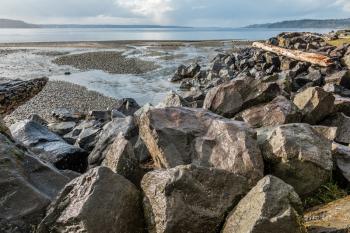 A creek flows past boulders into the Puget Sound at Saltwater State Park in Des Moines, Washington.