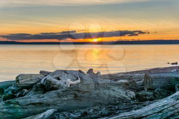 A view of the sun setting with driftwood in the foreground. Photo take from Normandy Park, Washington.