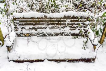 Snow covers a bench swing.