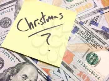 American cash money and yellow post it note with text Christmas with question mark in black color aerial view