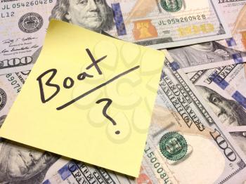American cash money and yellow post it note with text Boat with question mark in black color aerial view