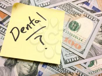 American cash money and yellow post it note with text Dental with question mark in black color aerial view
