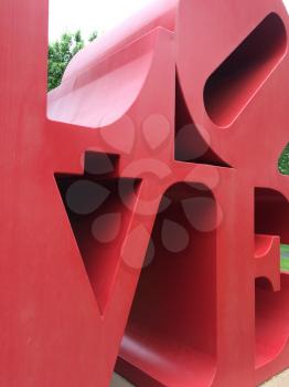 Love art text in big red metal letters in park with grass