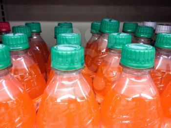 Plastic bottles orange soda cases stacked in supermarket background pattern