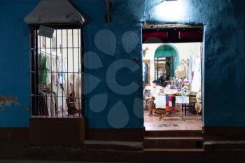 Trinidad, Cuba - 3 February 2015: People working in small souvenir shop at night