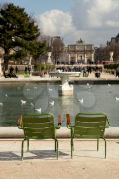 2 green and empty chairs at the Grand Bassin Rond in the Tuileries Garden, in Paris, France