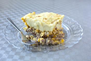 Shepherds pie or canadian pate chinois mash potatoes with meat and corn with fork in a transparent plate