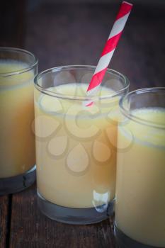 Three banana smoothies with a striped red straw on a row