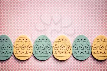 Decorated felt easter eggs yellow and blue on a pinky polka dots background.  Vintage style.