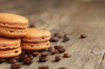 Three coffee macarons on a table with coffee beans