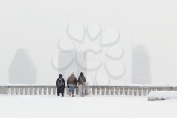 3 tourists looking at Montreal downtown under a snowstorm during winter