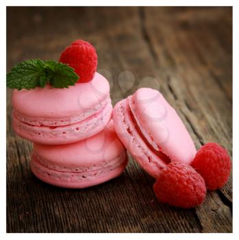 Pink macarons with raspberry on a rustic background