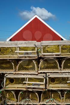 Yellow lobster cage in front of a red barn in Prince edward island, Canada