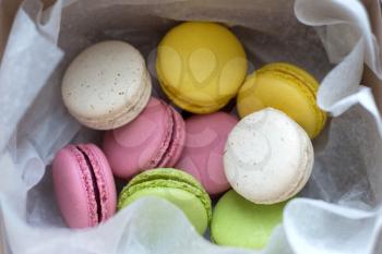 Colourful traditional macarons offered in a box and paper