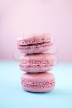 Stack of french traditional pink macarons on pink and pastel blue background