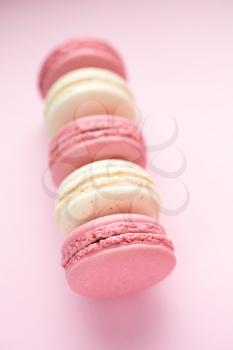 Row of traditional french macarons on pink background