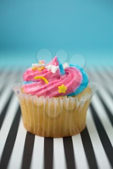 Cupcake with blue and pink icing on a black and white lined background