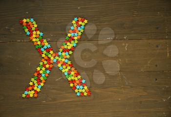 Letter X from alphabet made with star shape candy on a wooden background