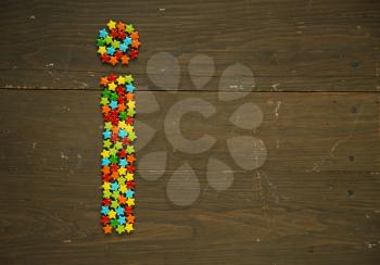 Letter I from alphabet made with star shape candy on a wooden background