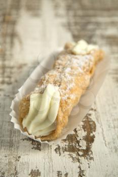 Cannoli in a paper on a grunge wooden background