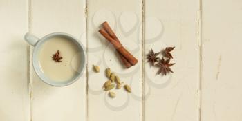 Top view of a chai tea with cinnamon, anise and cardamom on a white wooden background