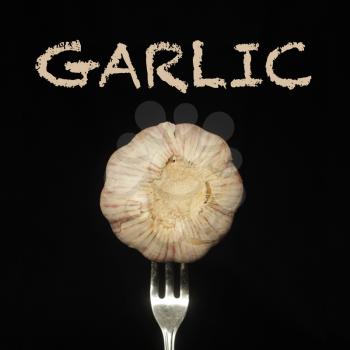 Garlic on a fork on a black background