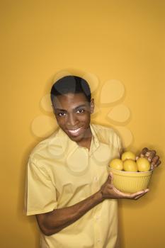 Royalty Free Photo of a Smiling Young Man Holding a Bowl of Lemons