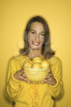 Royalty Free Photo of a Smiling Woman Holding a Bowl of Lemons