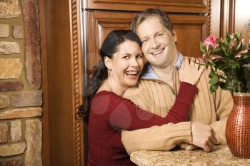 Royalty Free Photo of a Woman With Arms Around a Man in the Kitchen Smiling