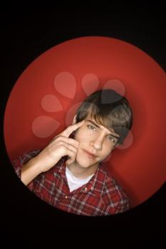 Portrait of Caucasian teen boy pointing to his head.