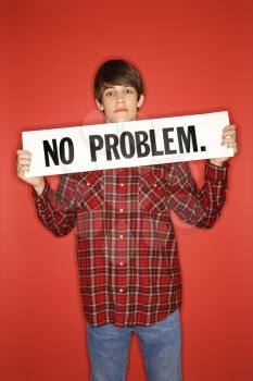Portrait of Caucasian teen boy holding no problem sign under his chin.