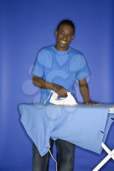Royalty Free Photo of a Teen Boy Ironing His Shirt