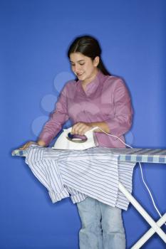 Royalty Free Photo of a Teen Girl Ironing a Shirt