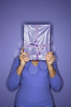 African American mature adult female holding present in front of face.
