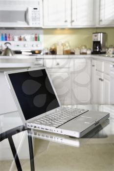 Royalty Free Photo of an Opened Laptop Computer on Top of a Glass Top Kitchen Table