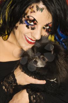 Royalty Free Photo of a Woman in Unique Makeup Holding a Black Pomeranian Dog