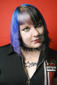 Royalty Free Photo of a Woman With Blue Hair, Tattoos, and a Spike Collar Against an Orange Background