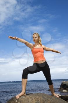 Royalty Free Photo of a Young Woman Doing Yoga on a Rocky Shore