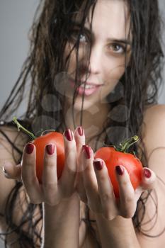 Caucasian woman holding a pair of tomatoes.