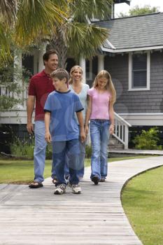 Royalty Free Photo of a Family Walking Down a Suburban Sidewalk With a House in the Background