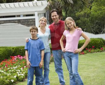 Caucasian family of four posing for portrait in yard.