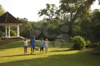 Royalty Free Photo of a Family of Four Walking in the Park Carrying a Picnic Basket