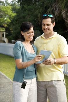 Mid-adult Caucasian couple holding map and smiling. 