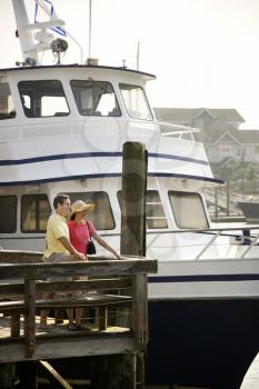 Mid-adult Caucasian couple at dock with boat in background.